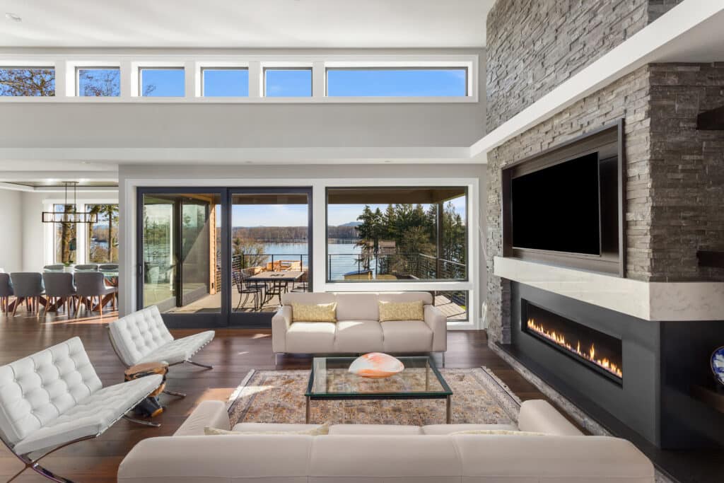 Beautiful living room in new luxury home with large stone fireplace and lots of natural light