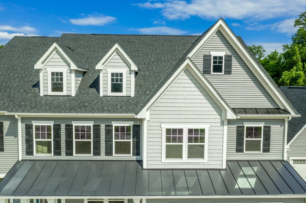 Exterior second story of a light gray house with dormer windows